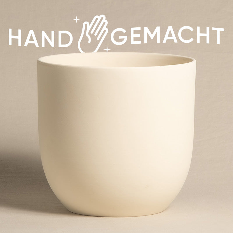 Ein glatter, cremefarbener, heller Keramik-Topf (Direito | 22 cm ⌀) ist zentriert vor einem schlichten beigen Hintergrund. Über dem Übertopf sind die Worte „HAND GEMACHT“ in Weiß geschrieben, mit einem Handsymbol und Glitzer zwischen den Worten.