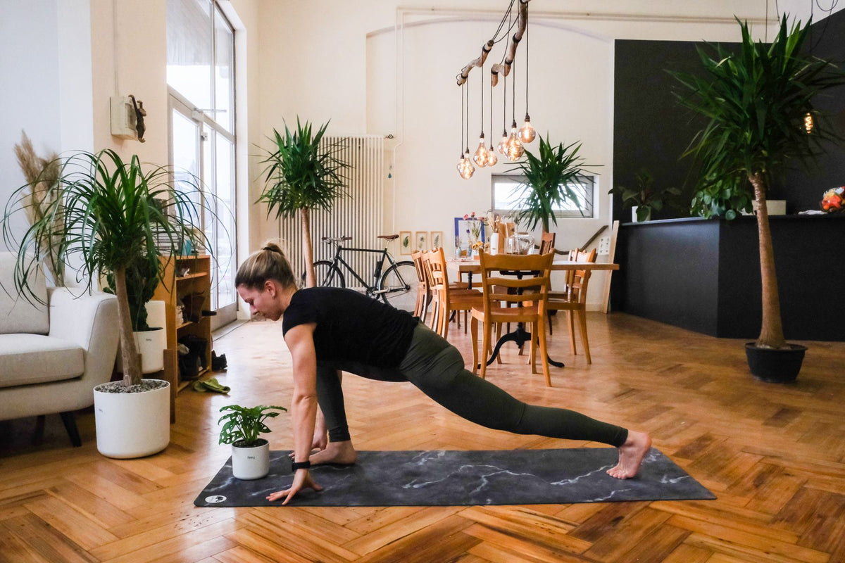 Plant-Yogi Hanna stellt den rechten Fuss zwischen die Hände, der linke ist gestreckt