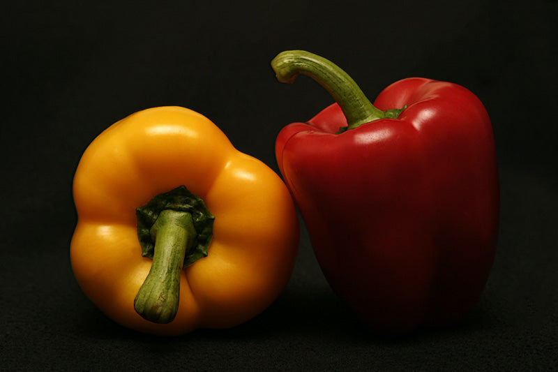 Gelbe und rote Paprika vor schwarzem Hintergrund