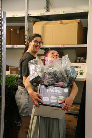 Vani mit vollbepackten Armen und Yasmine, die im Hintergrund lacht.